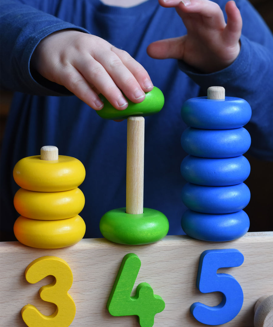 A close up of a child playing with a Bajo 1-5 pull along stacking toy