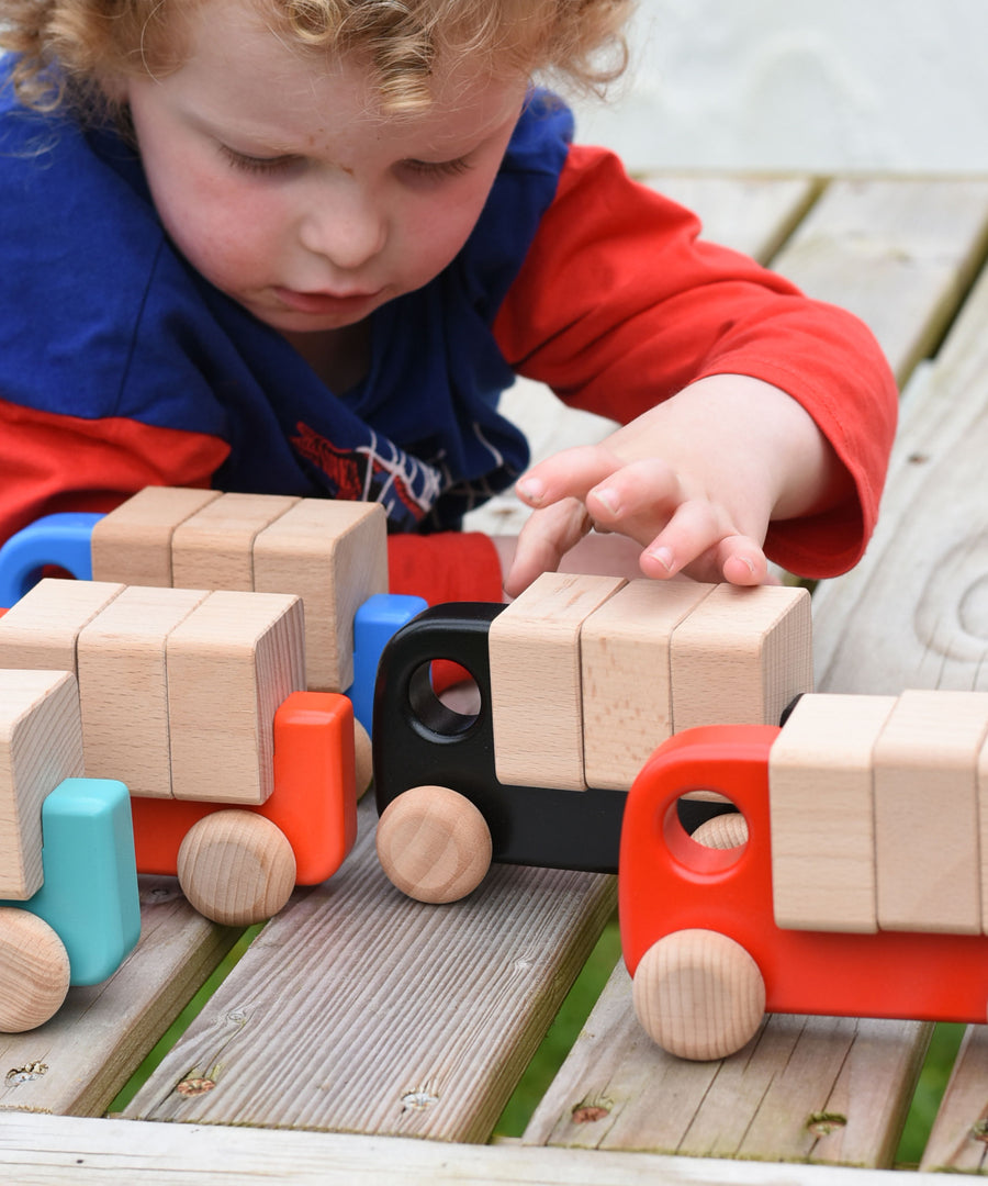 A child playing with a collection of Bajo trucks