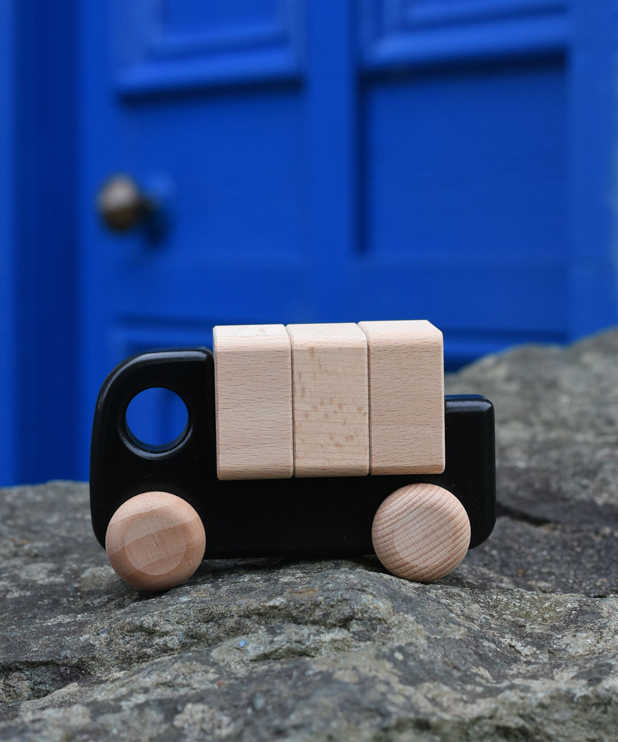 A black Bajo truck with blocks on a stone wall 