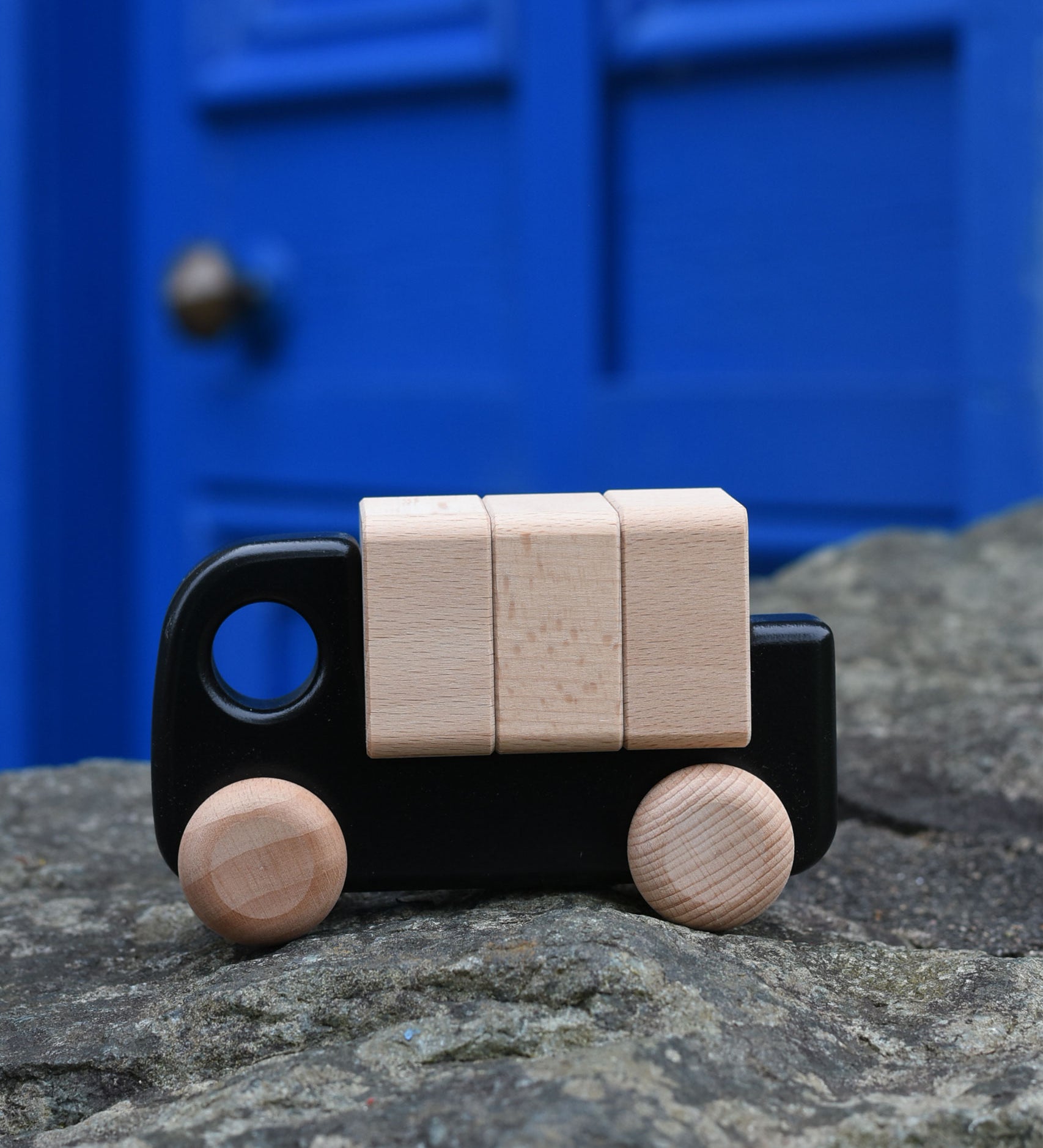 A black Bajo truck with blocks on a stone wall 