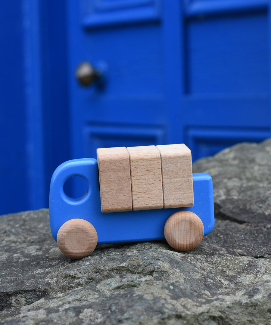 A blue coloured Bajo truck with blocks placed on a stone wall