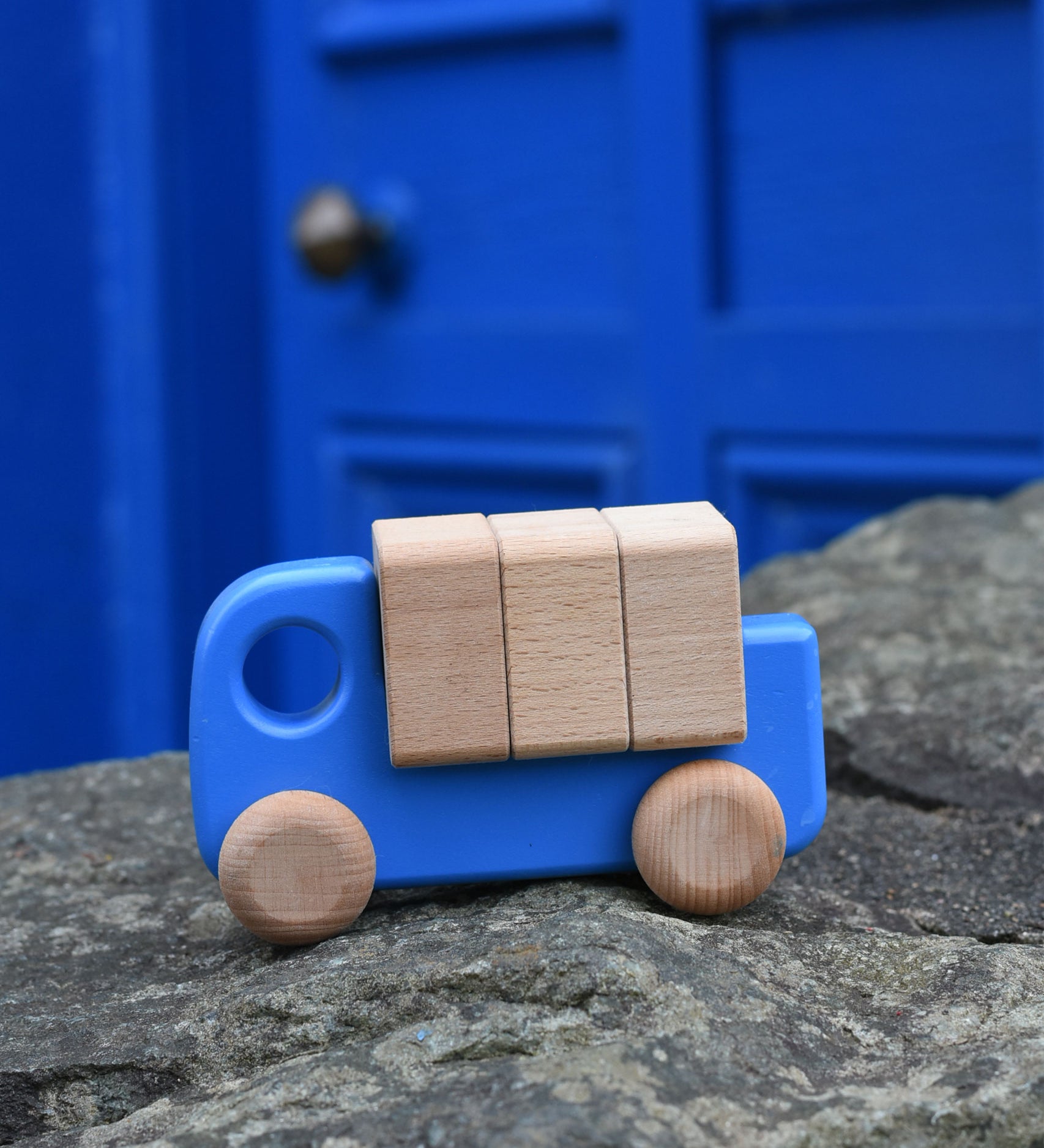 A blue coloured Bajo truck with blocks placed on a stone wall