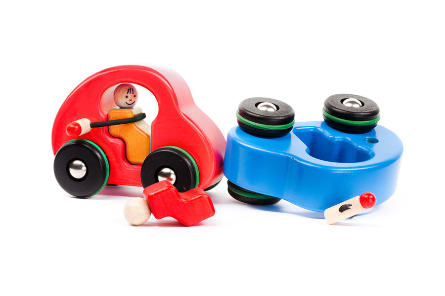 Eco-friendly Bajo fasten seatbelts car on a wooden background in front of a wooden tree toy and a red bajo fasten seatbelts car