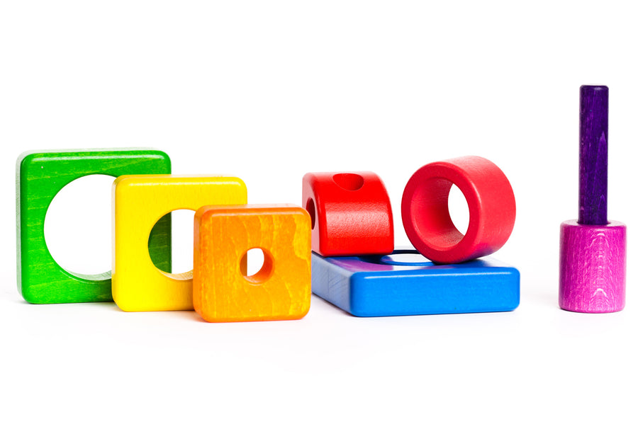 Pieces of the Bajo plastic-free wooden shape stacking toy laid out on a white background