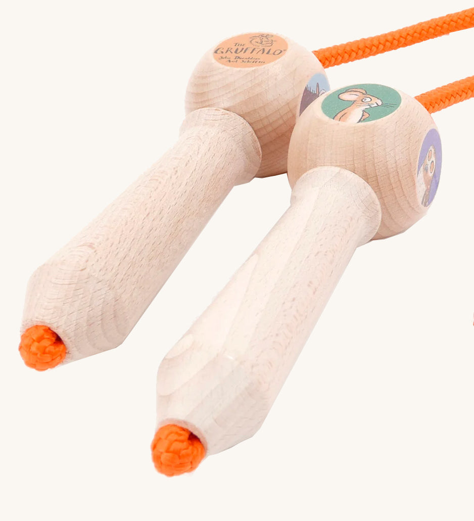 A close up of the wooden gruffalo skipping rope with orange rope on a cream background