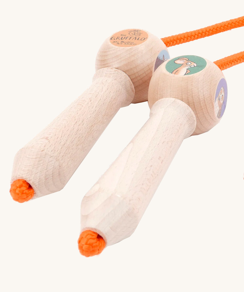 A close up of the wooden gruffalo skipping rope with orange rope on a cream background