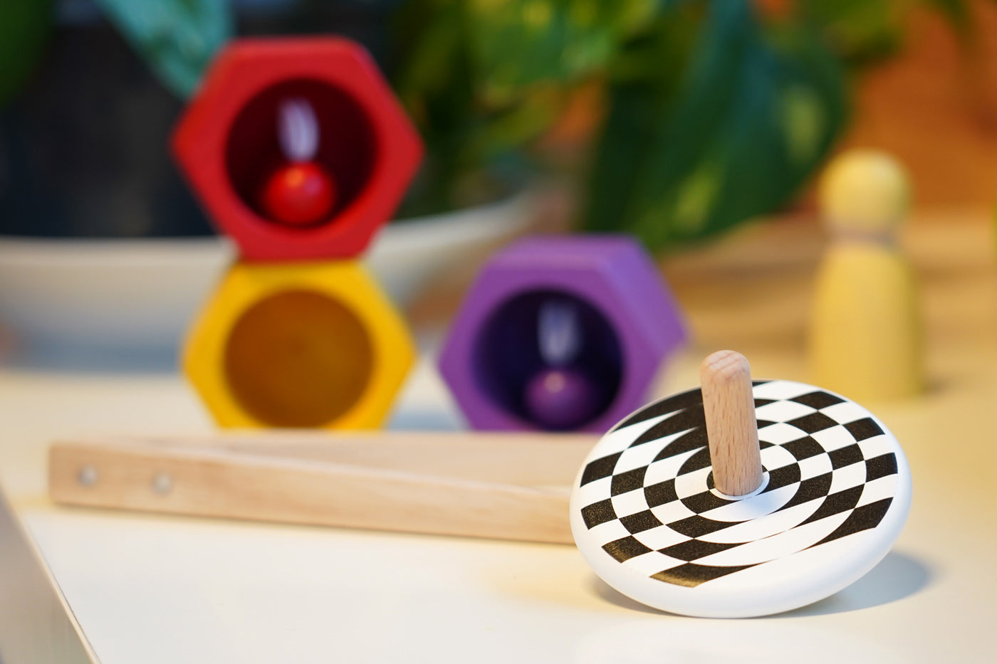 Bajo kids wooden latern spinning top on a white table next to some PlanToys Bee toys