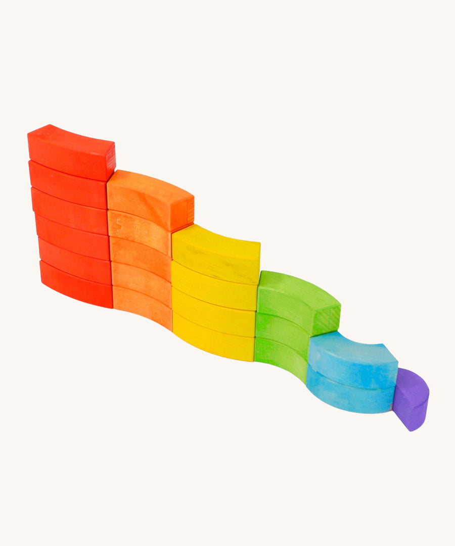 Bajo children's toy rainbow blocks set stacked in a curvy line on a white background