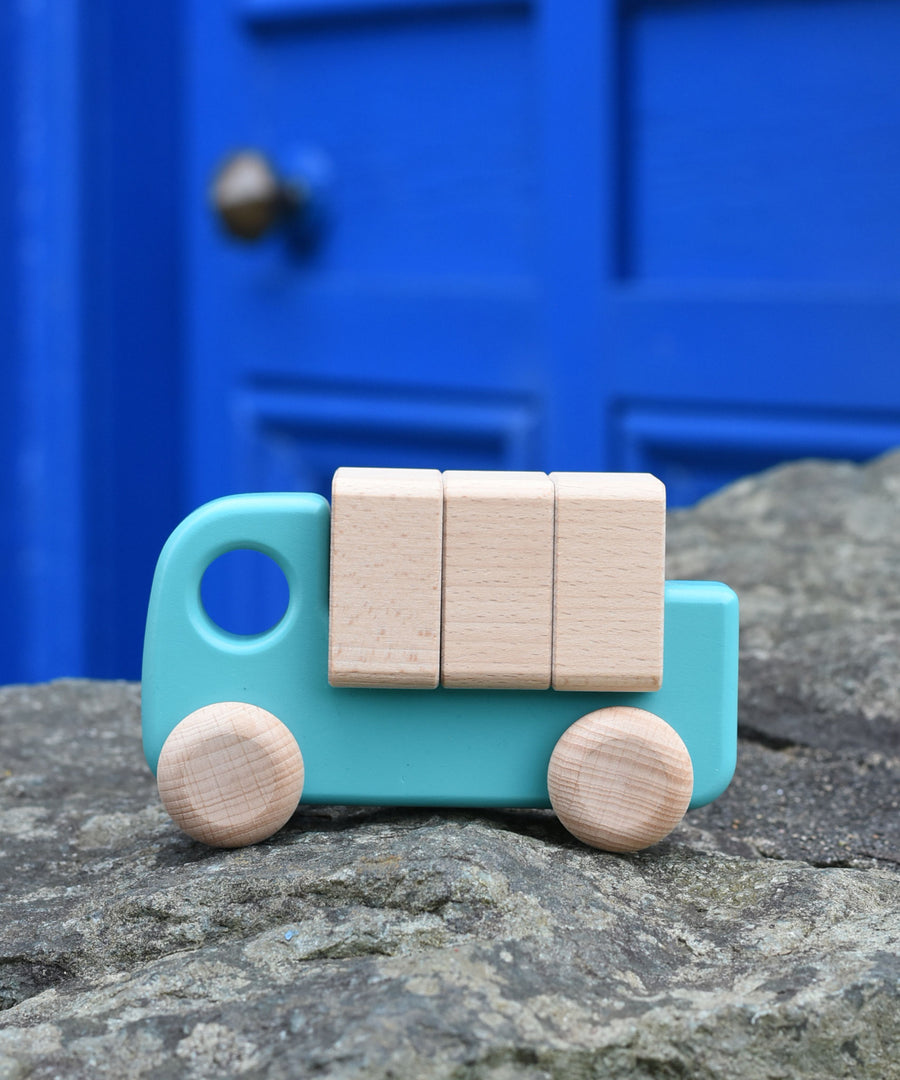 A light blue coloured Bajo truck with blocks placed on a stone wall 