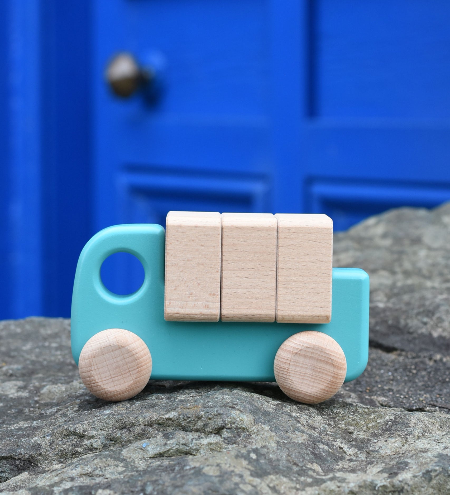 A light blue coloured Bajo truck with blocks placed on a stone wall 