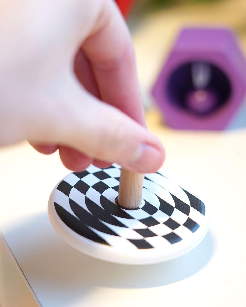 Close up of a hand spinning the Bajo children's wooden latern spinning top