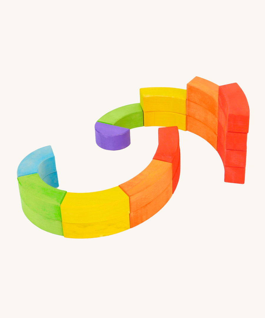 Bajo plastic-free wooden rainbow blocks laid out in 2 spirals on a white background