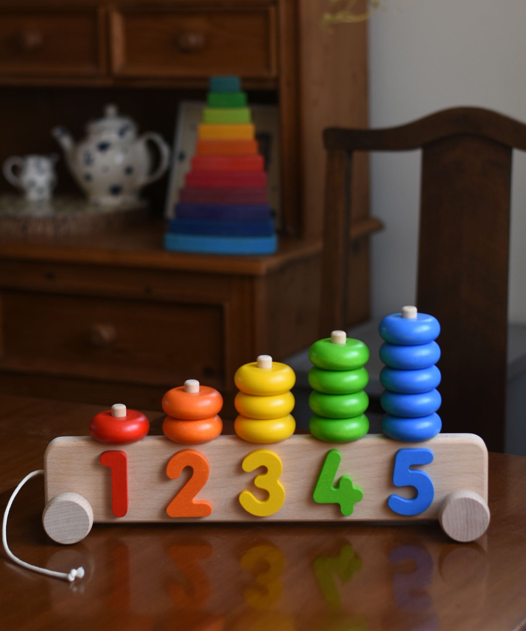 A Bajo 1-5 Pull Along Stacker on a wooden table. A Grimm's Wankel stacking toy can be seen in the background. 