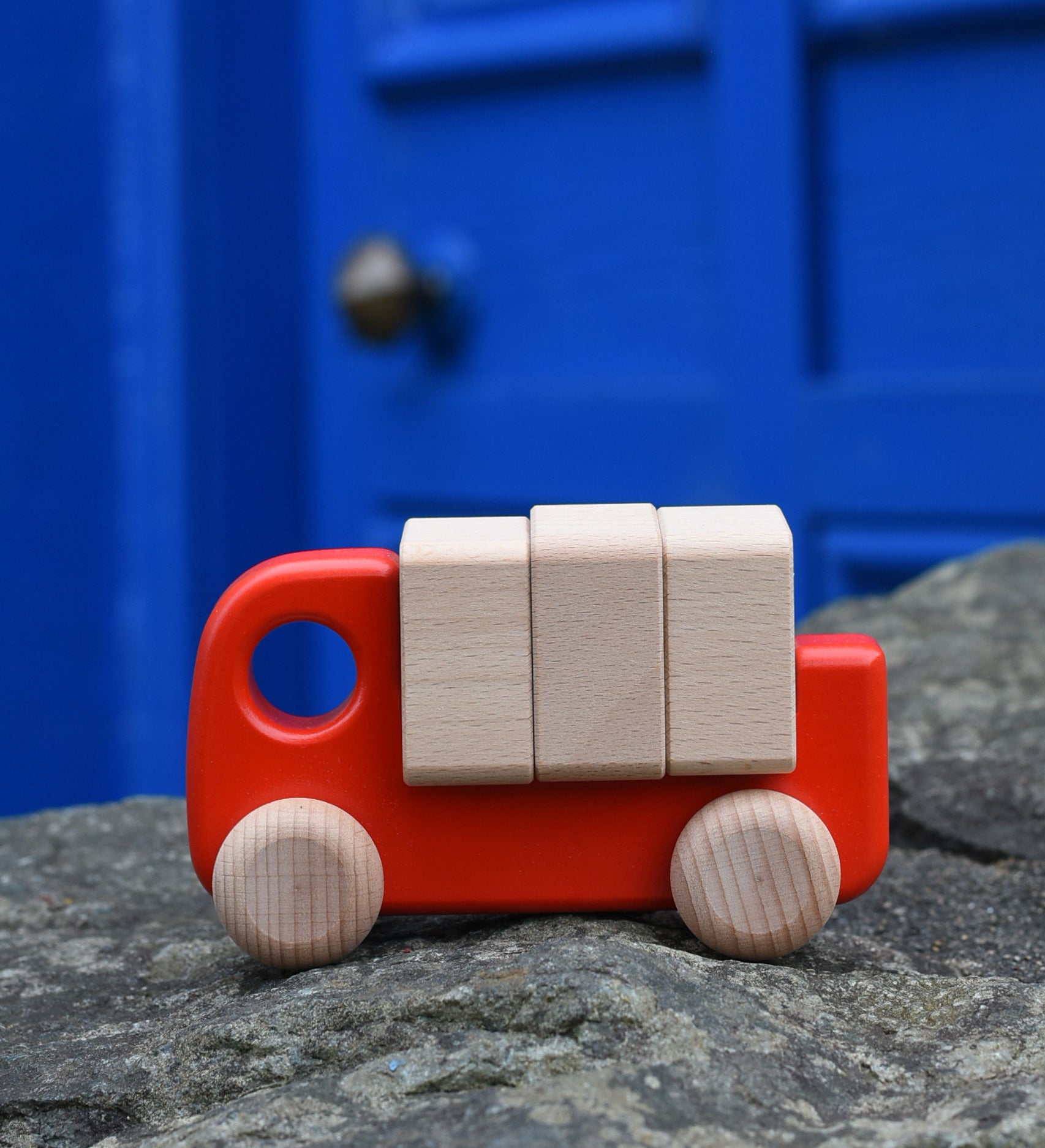 A red Bajo truck with blocks placed on a stone wall