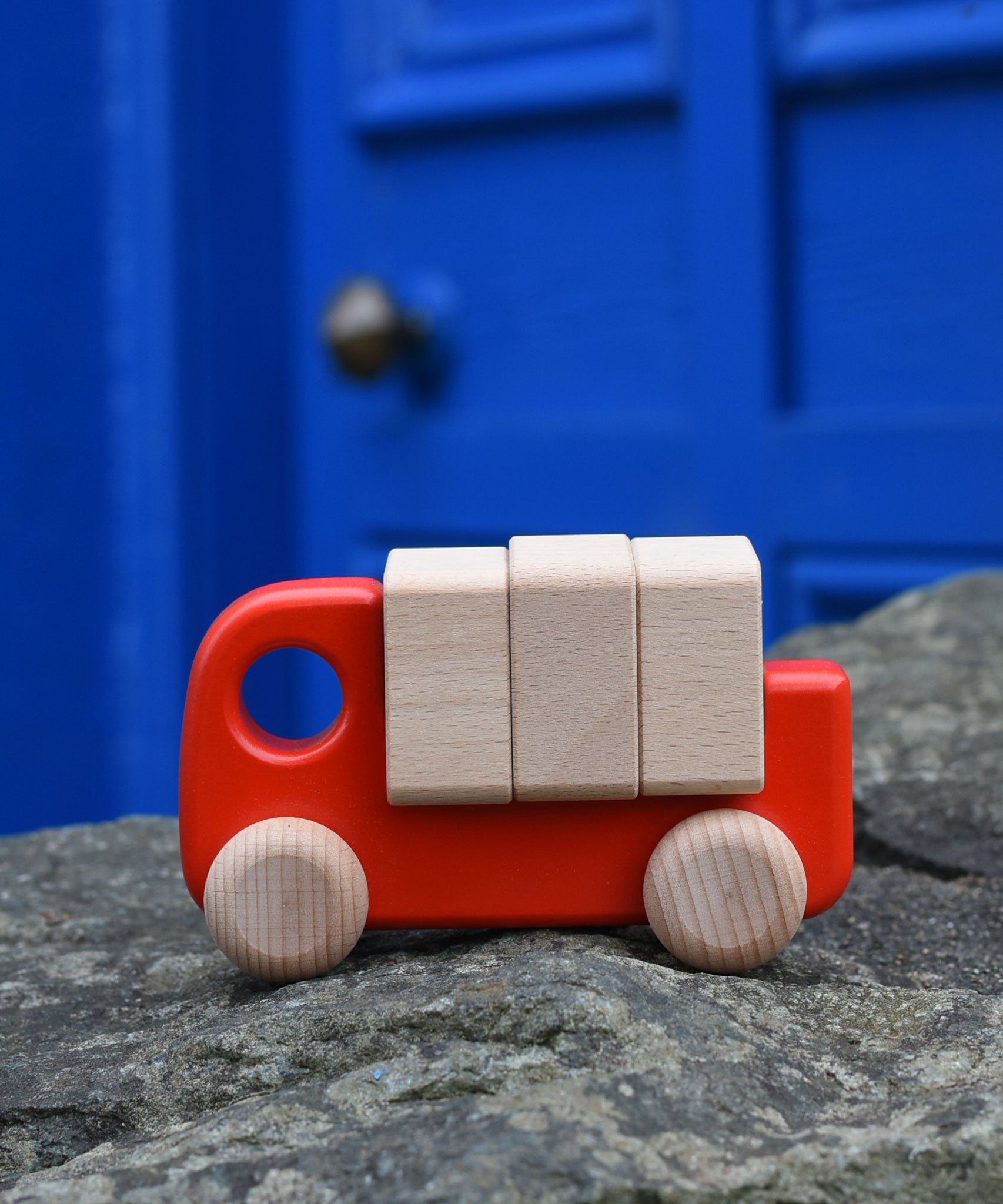 A red Bajo truck with blocks placed on a stone wall