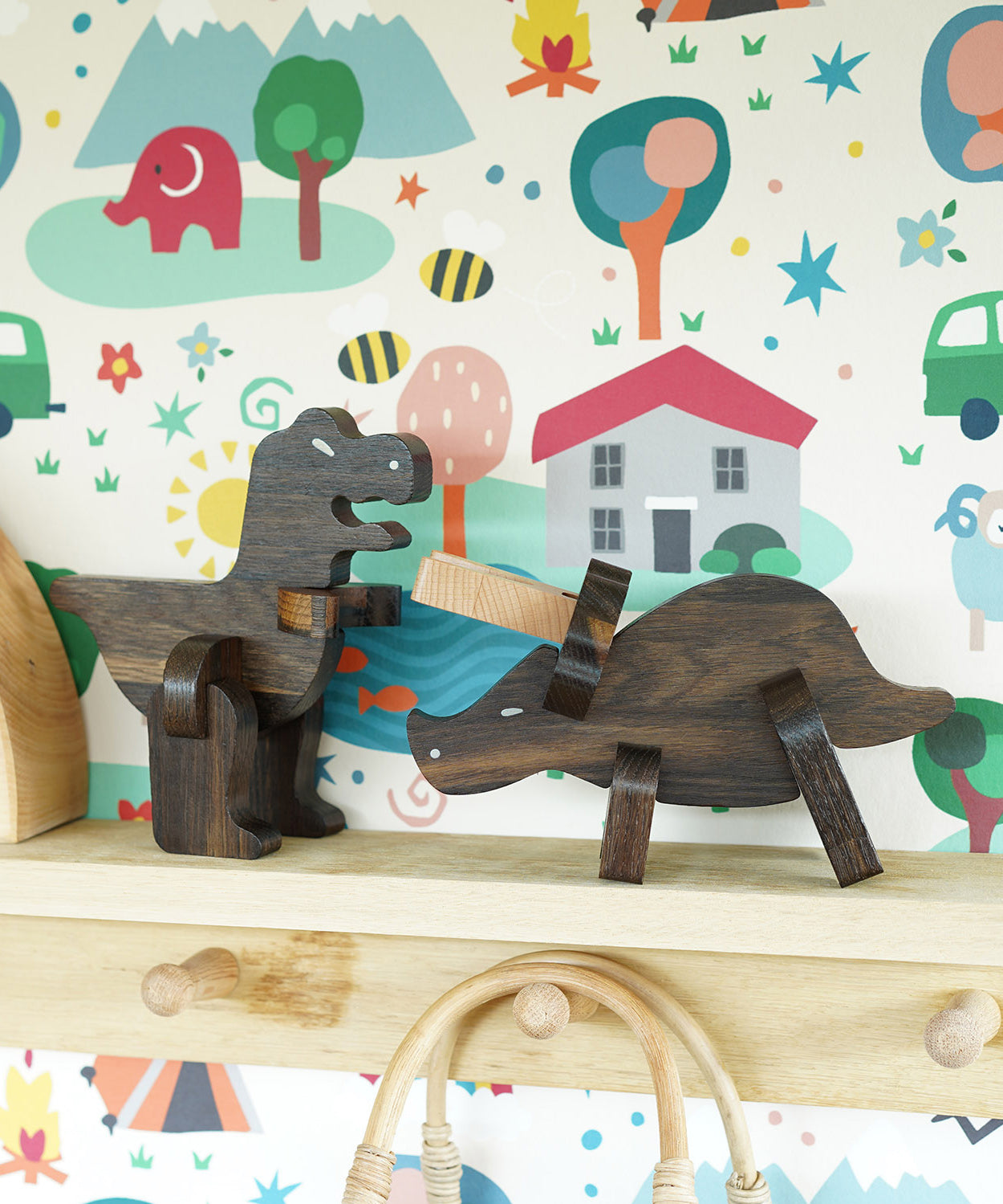 Bajo Puzzle & Sorter - Black Oak T-Rex and Triceratops on a wooden shelf with a colourful background