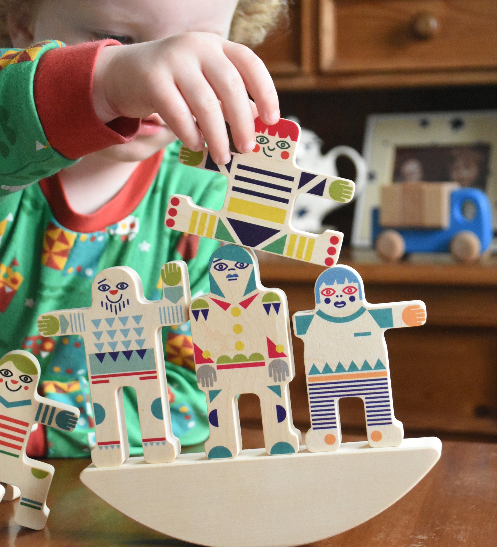 A child playing with the Bajo world balance game. Th echild has stacked 3 pieces on the base and had another in his hand that he is placing on top.