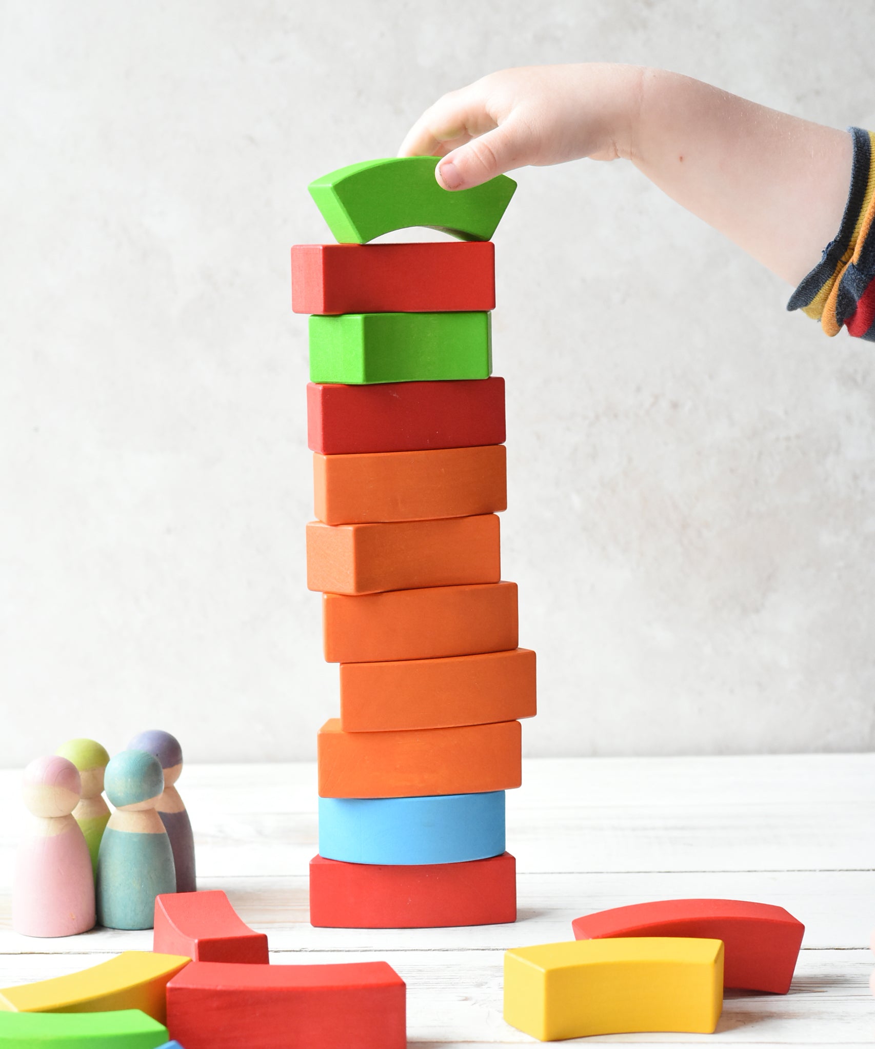 A person stacking the Bajo Rainbow Blocks on top of each other making a horizontal stack