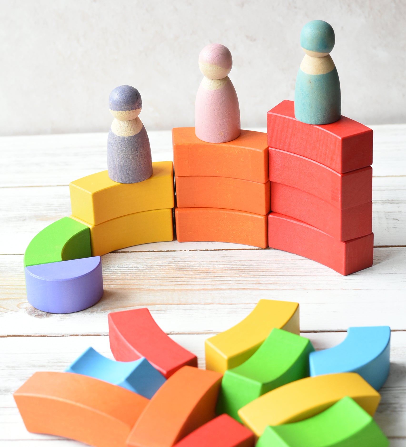 Grimm's figures stood on top of the Bajo plastic-free stacking wooden rainbow blocks