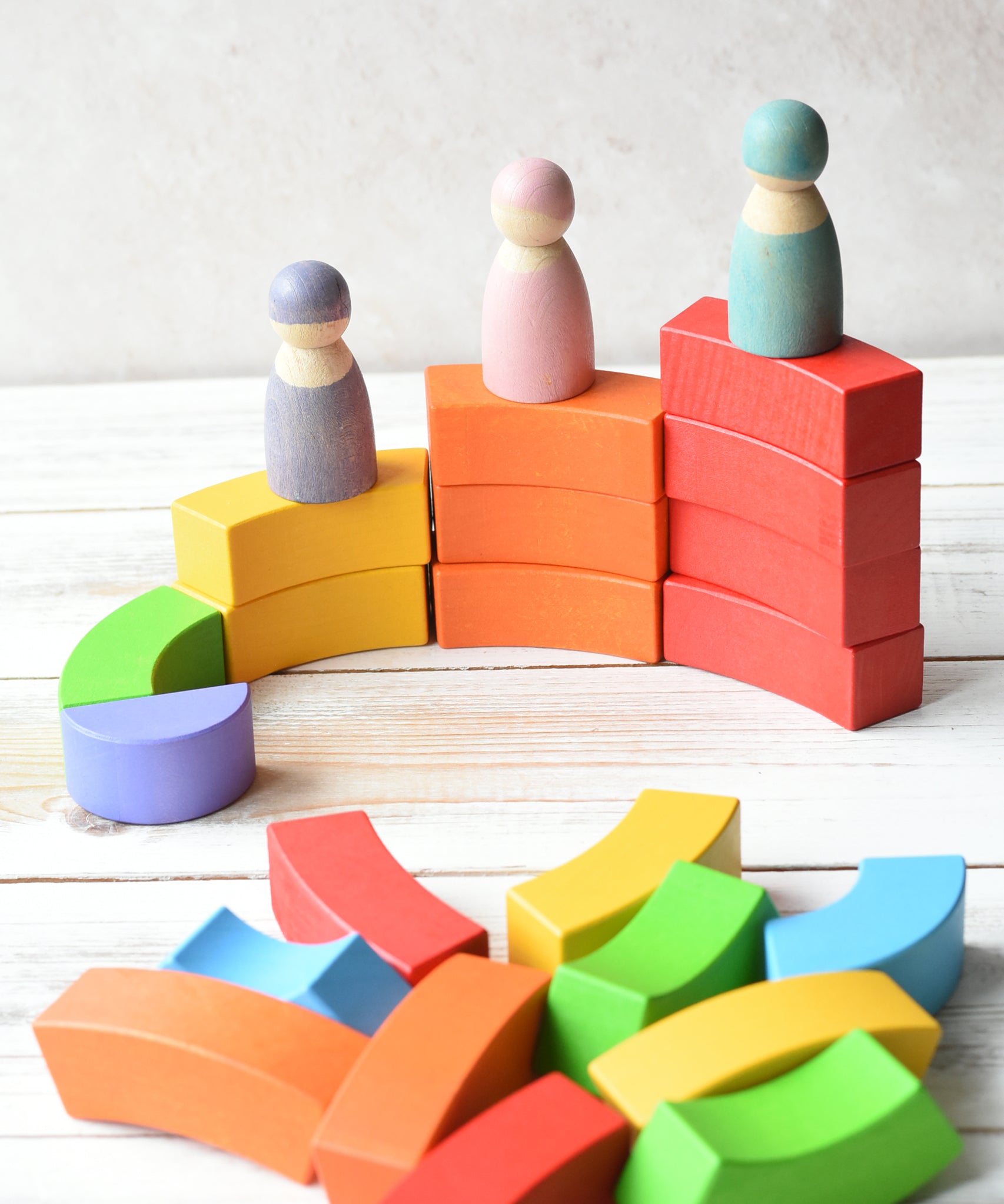 Grimm's figures stood on top of the Bajo plastic-free stacking wooden rainbow blocks