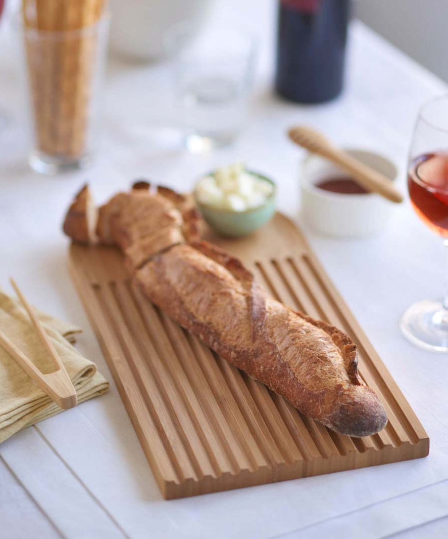 A Bambu bamboo Arch Bread Board with a baguette on it. 