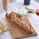 A Bambu bamboo Arch Bread Board with a baguette on it. 