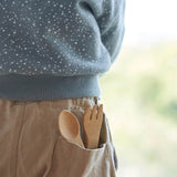 The Bambu Bamboo kids fork and spoon shown pepping out of a child's back pocket.