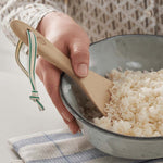 A Bambu Bamboo Rice Paddle in a bowl of rice being held by a person. 