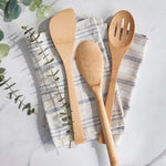 Three utensils from the Bambu Give It a Rest bamboo utensils range placed on folded tea towels on a marble surface. 