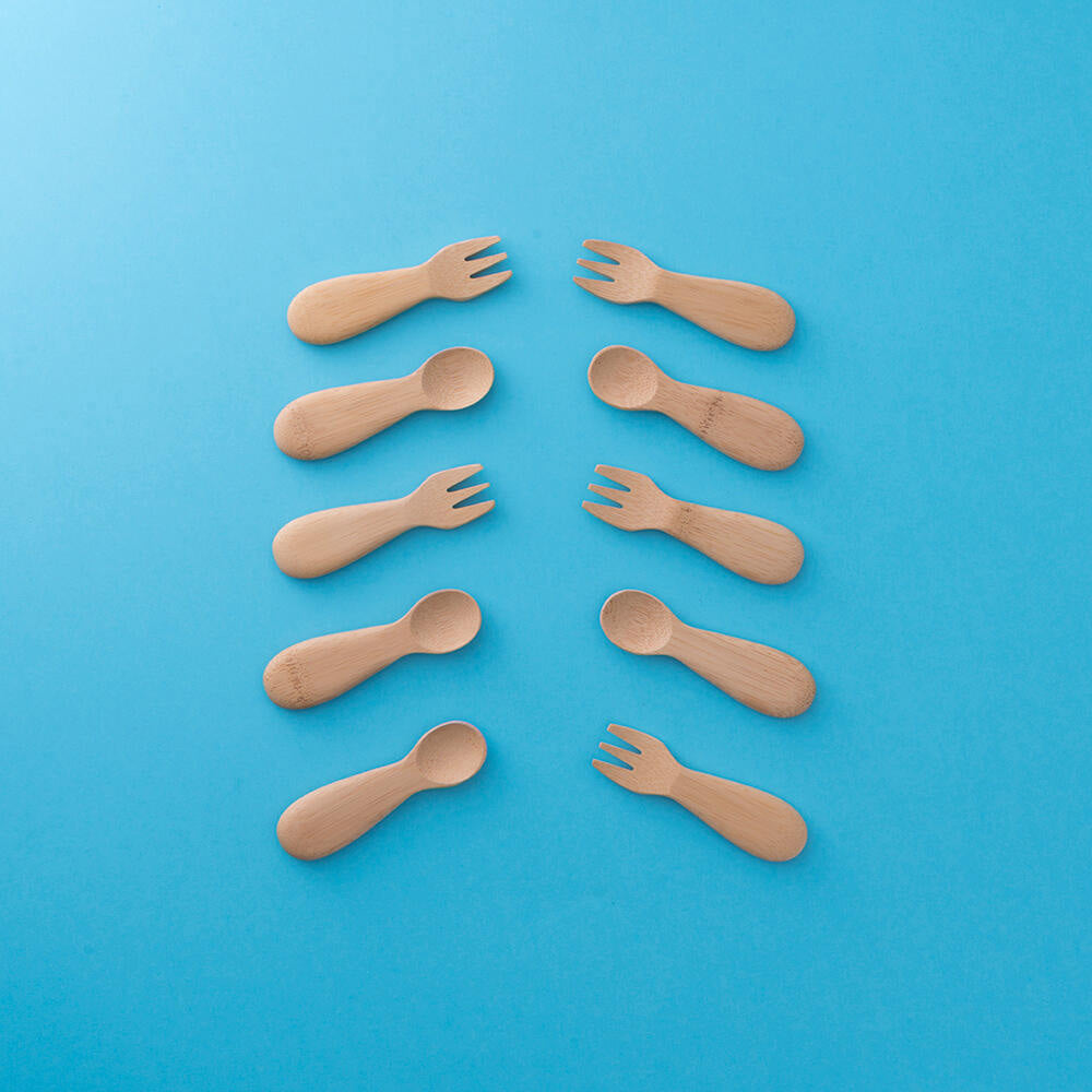 lots of Bambu bamboo baby spoons and forks pictured on a plain blue background 