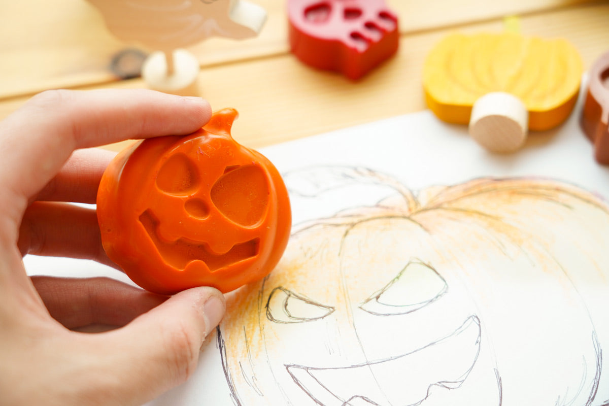 Close up of hand colouring in a pumpkin drawing with the bee crayative large pumpkin coloured crayon