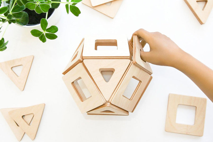 Close up of a hand placing a Big Future Toys earth tile into a geometric ball shape on a white background