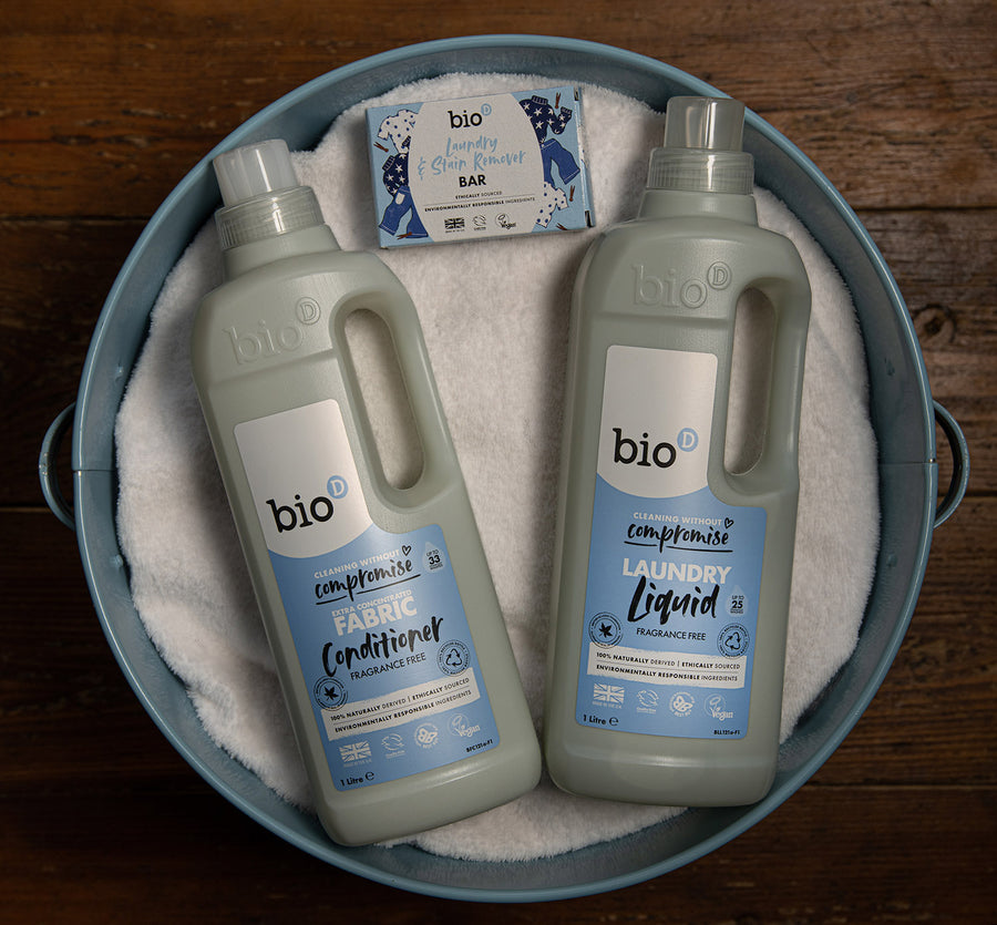 Bio-D fragrance free fabric conditioner 1 litre bottle on a blue back ground surrounded by white clothes