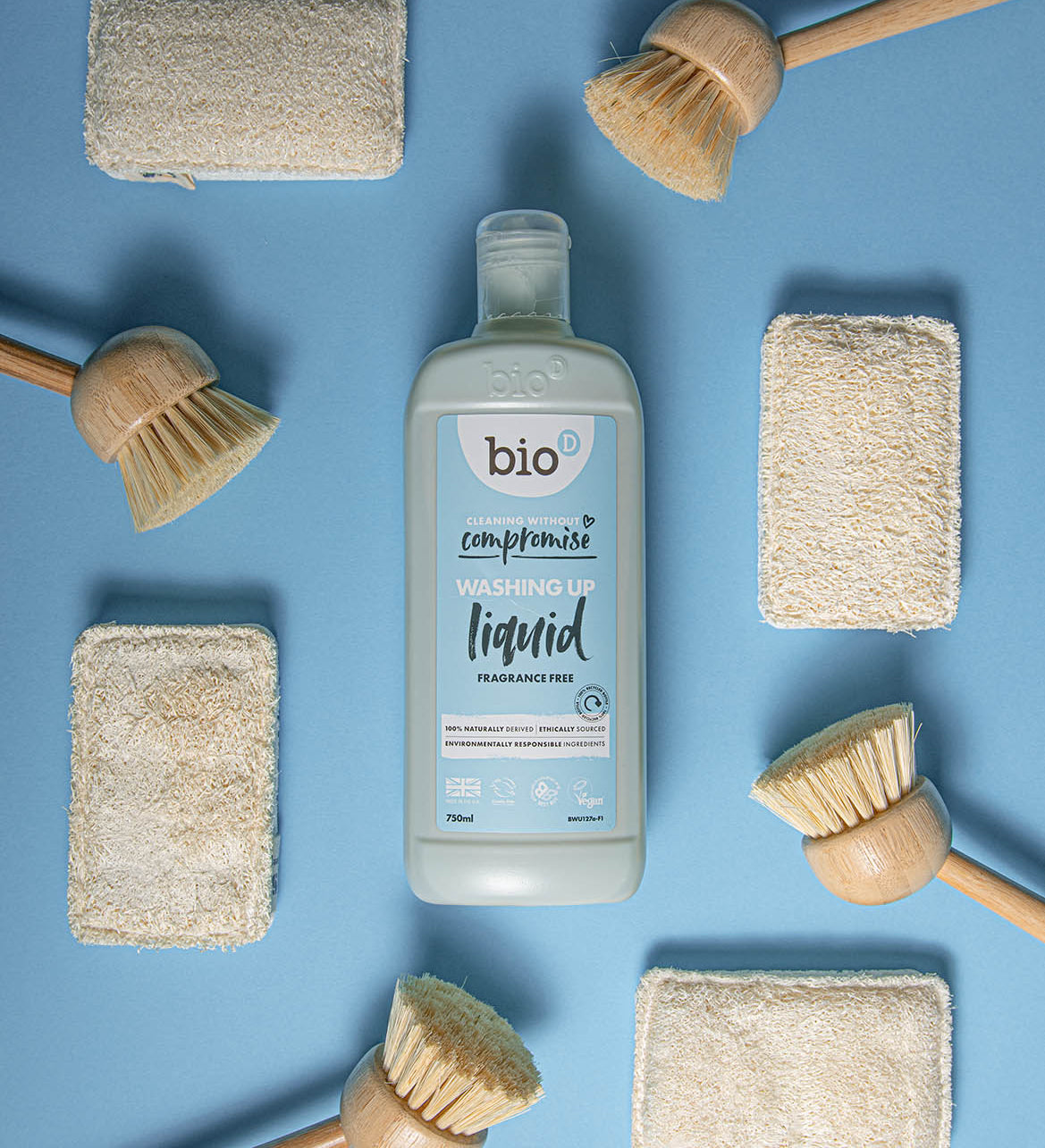 Bio-D Fragrance Free natural vegan friendly Washing Up Liquid in a 750ml bottle pictured on a blue back ground with wooden dish brushes and natural sponges