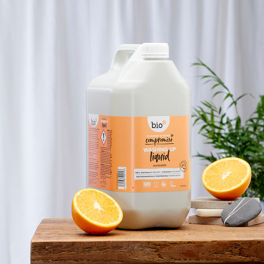 Bio-D natural mandarin eco-friendly 5 litre washing up liquid on a wooden table with a white back ground and green plant