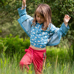 A child wearing the Little Green Radicals Kids Organic Cotton Blue Clouds Loose Fit Short Sleeve Henley Top with a striped blue shirt on top. 