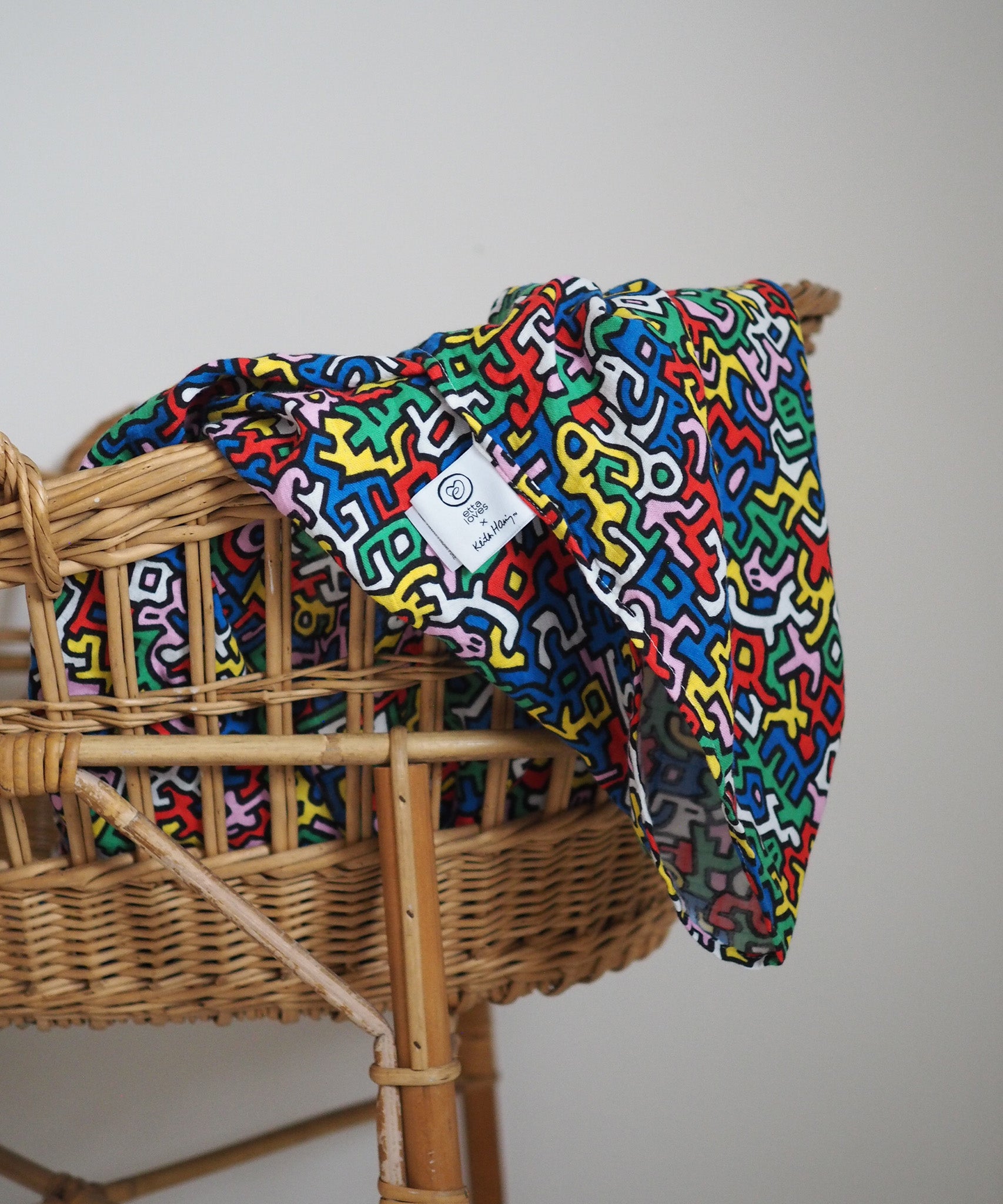 A baby graping and looking at the Etta Loves X Keith Haring Extra Large Organic Cotton Baby Muslin Square - Brazil