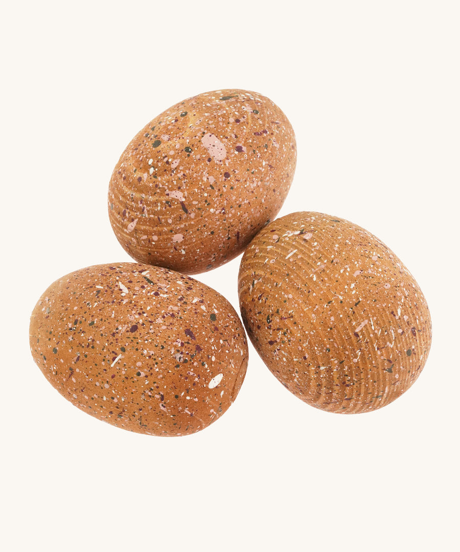 3 brown speckled wooden dinosaur eggs on a cream background