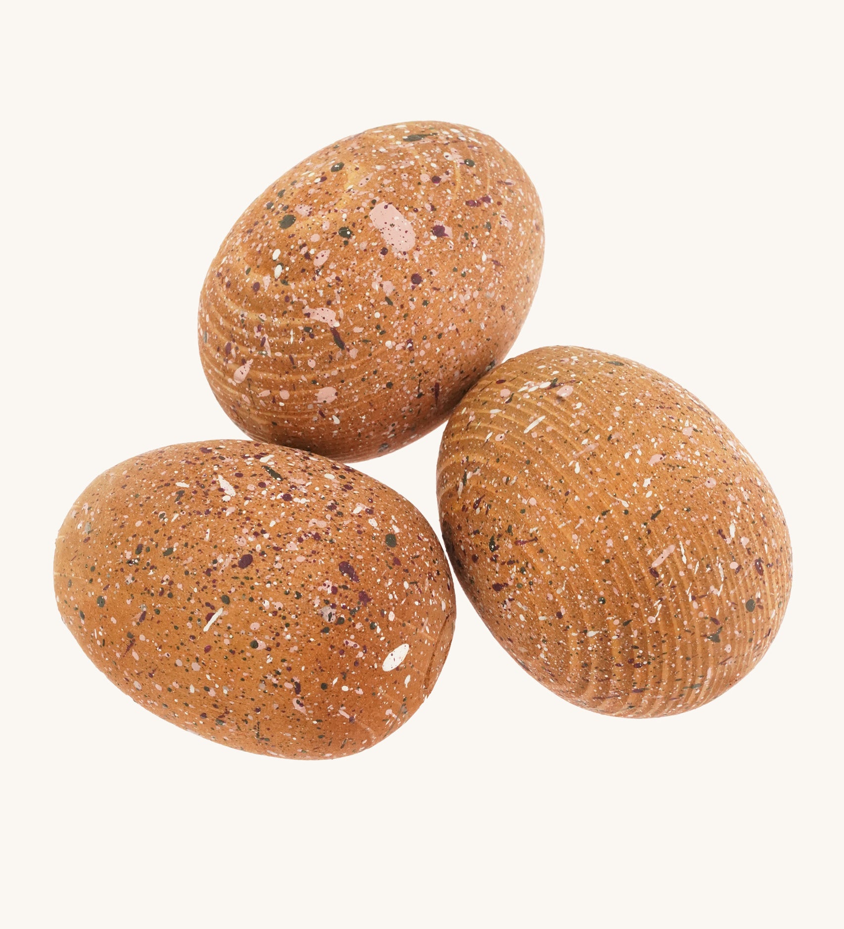 3 brown speckled wooden dinosaur eggs on a cream background