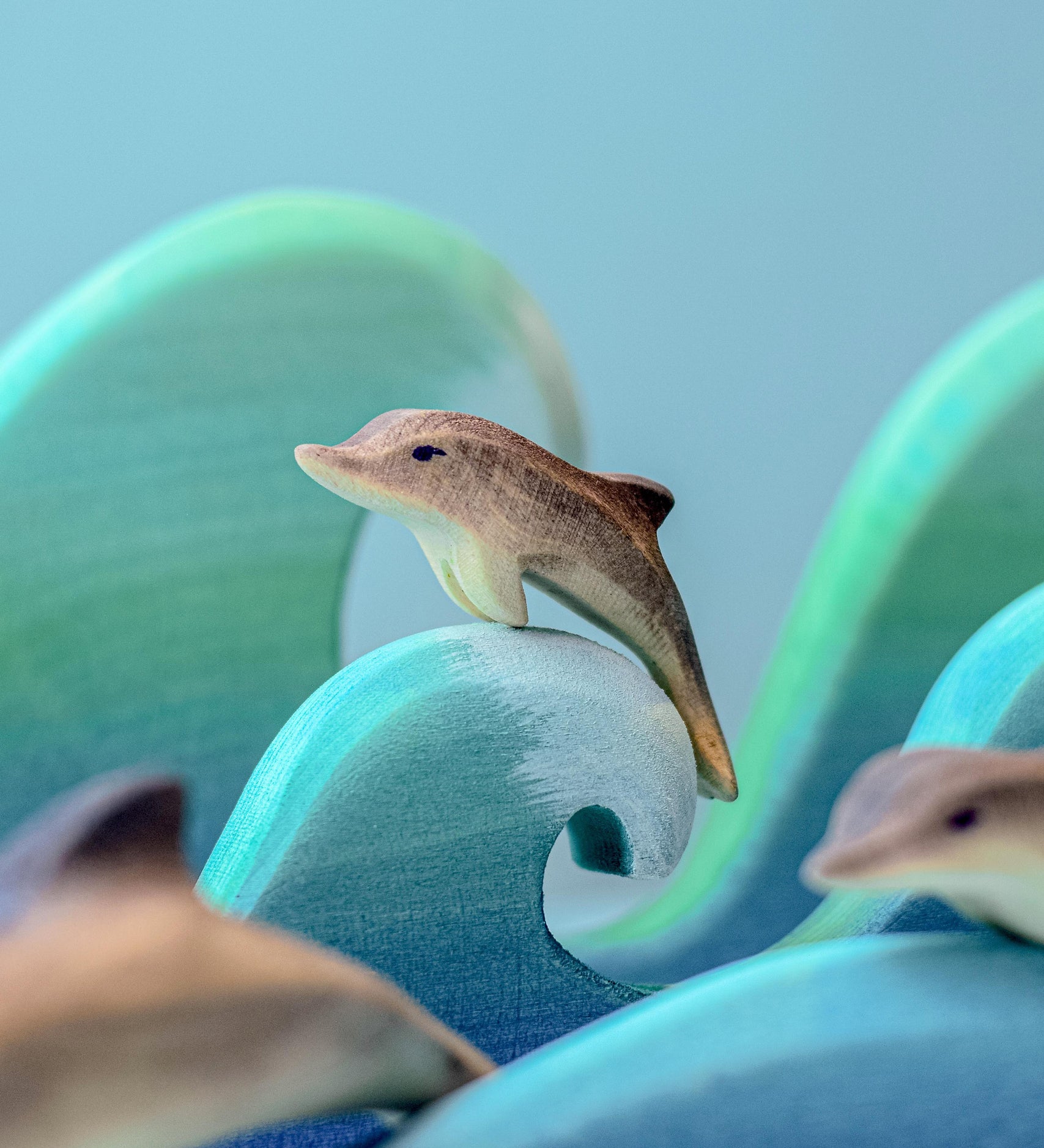 A Bumbu baby wooden dolphin perched on a wooden wave.