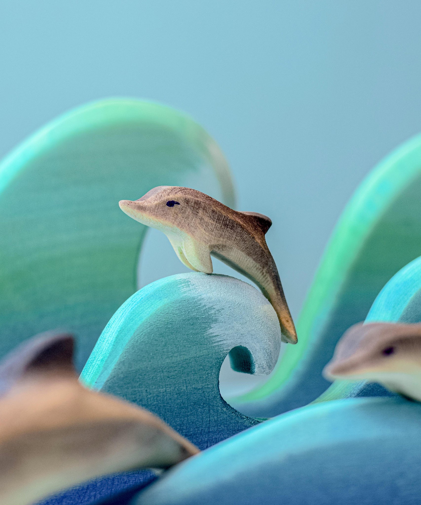 A Bumbu baby wooden dolphin perched on a wooden wave.