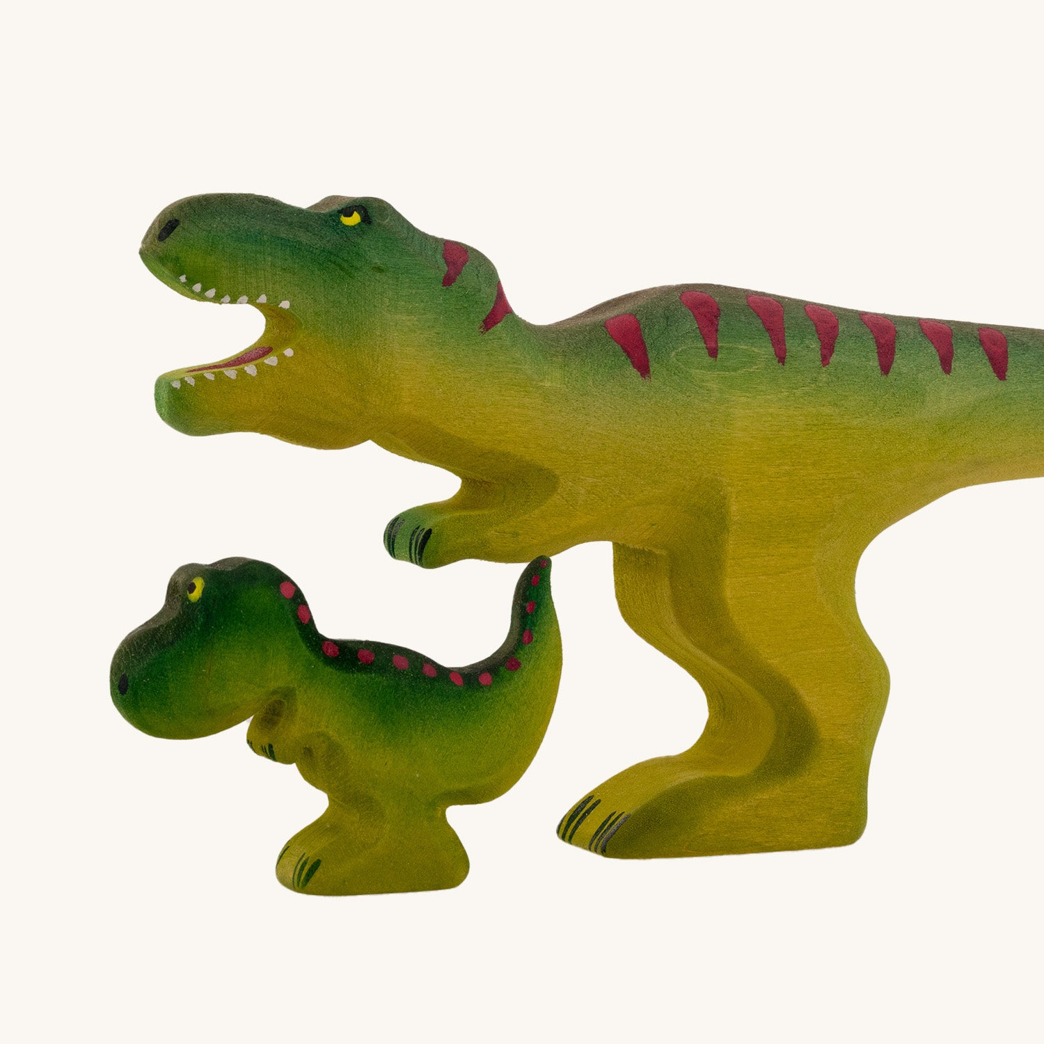 Wooden toy baby T-Rex in vibrant shades of green and purple. The baby T-Rex stands upright in a forward stance. The toy has painted eyes