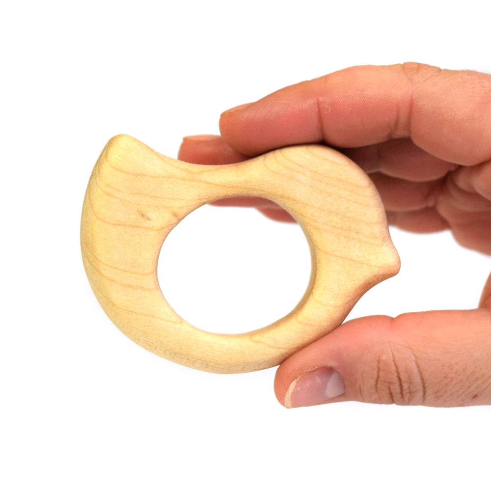 Close up of a hand holding the Bumbu plastic-free wooden bird baby teether on a white background