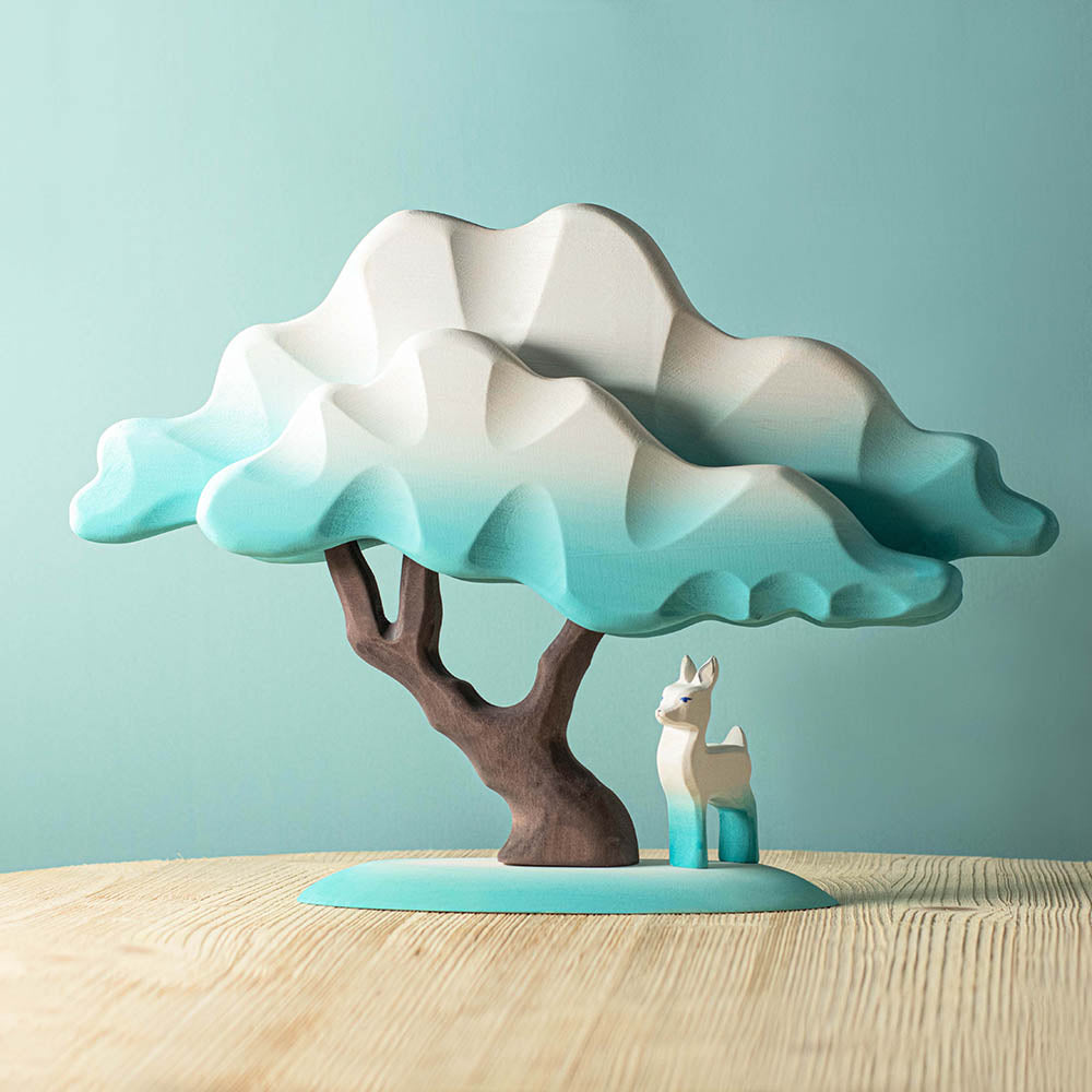 Bumbu blue Japanese winter maple tree toy on a wooden table next to a white and blue fawn figure