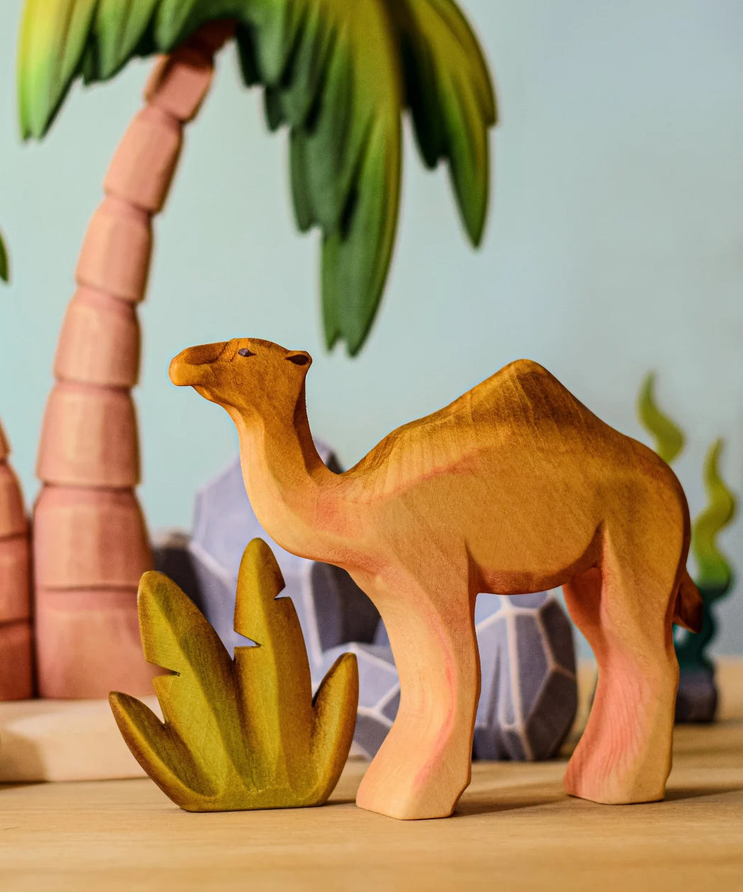 Bumbu handmade wooden camel figure standing in front of desert palm trees