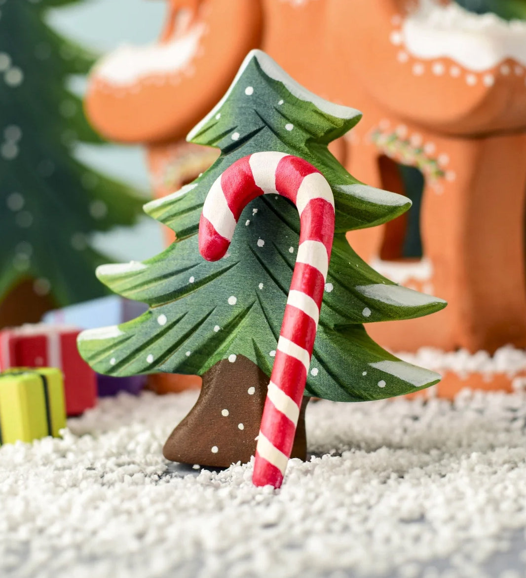 A red and white wooden Bumbu candy cane resting on the small Bumbu Christmas tree