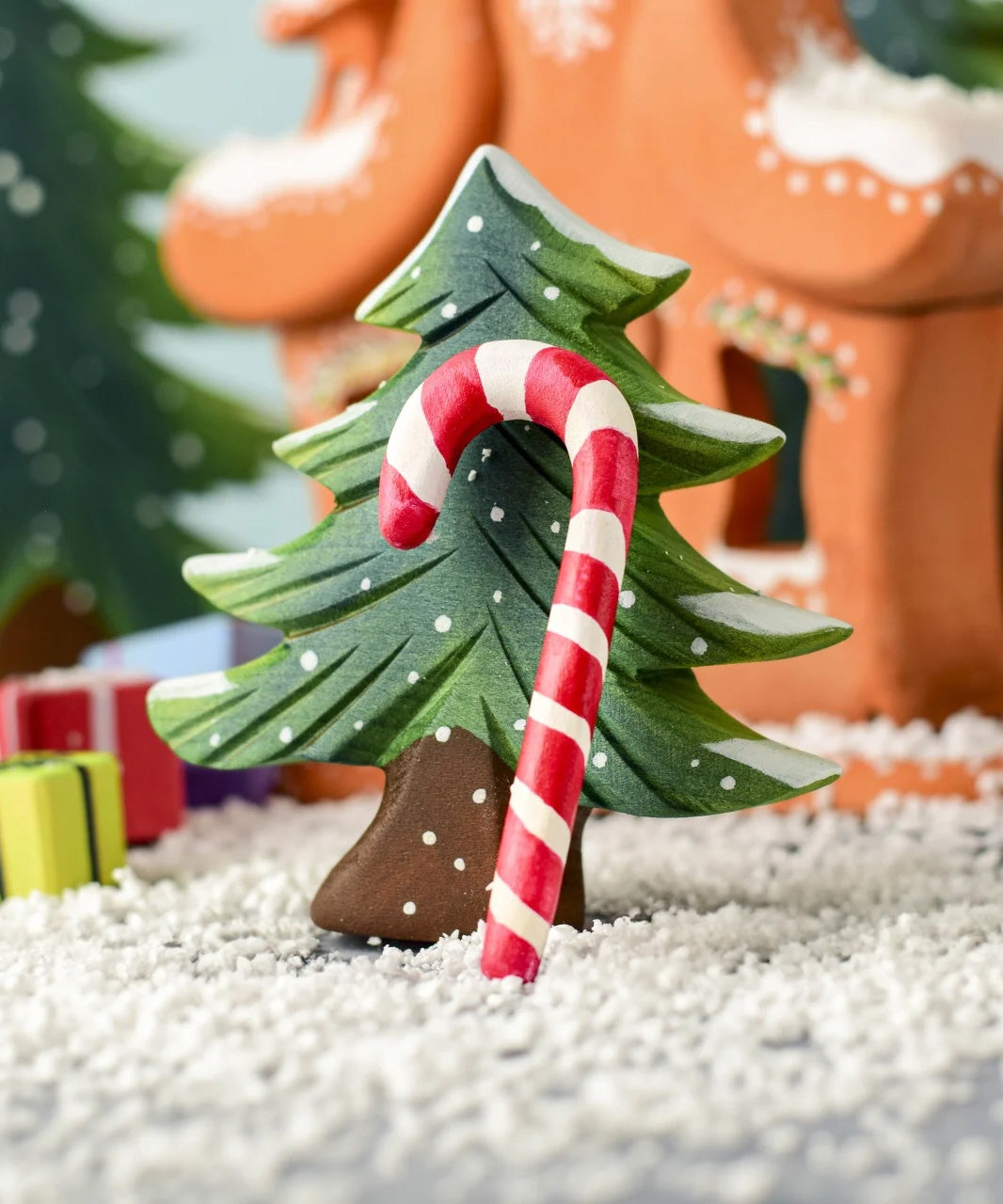 A red and white wooden Bumbu candy cane resting on the small Bumbu Christmas tree