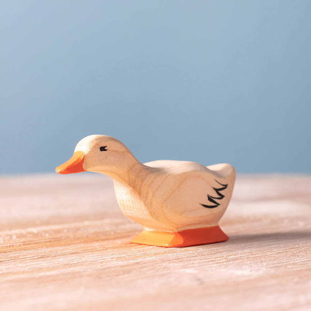 Bumbu childrens curious wooden duck toy on a wooden worktop in front of a blue background