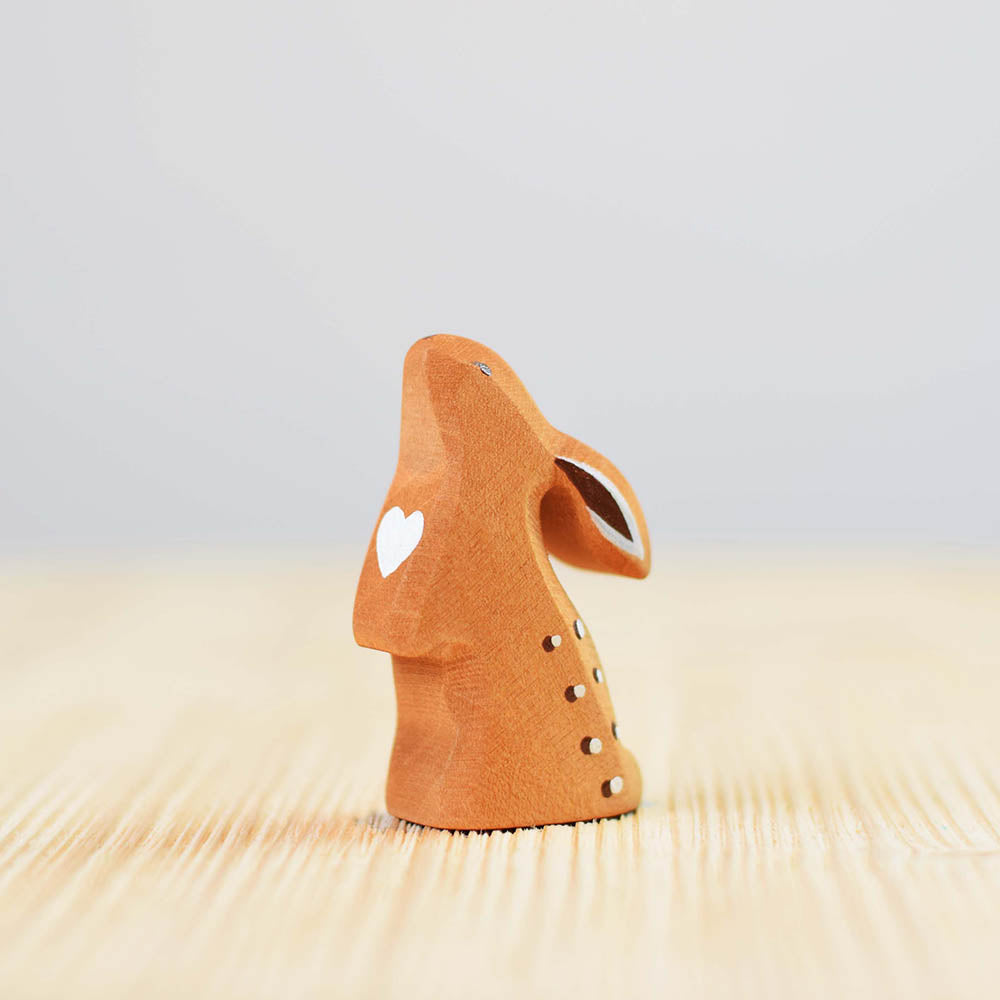 Close up of the Bumbu handmade wooden curious rabbit toy on a wooden worktop