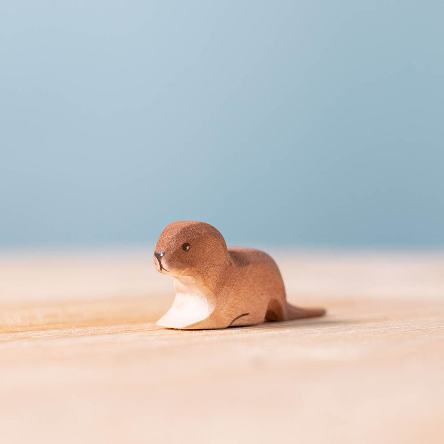 Close up of the Bumbu handmade wooden baby otter toy on a wooden suface